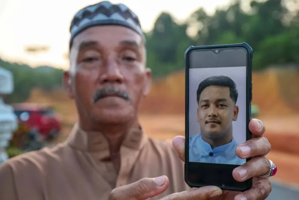 Pesara polis, Mazlan Umar, 64, menunjukkan gambar anaknya, Allahyarham Koperal Mohd Hafizul Izham maut selepas dirempuh kenderaan penjenayah yang sedang melakukan jenayah pecah rumah di Taman Golf, Alor Setar, Kedah, semasa ditemui di Kampung Pak Kancil. Foto Bernama