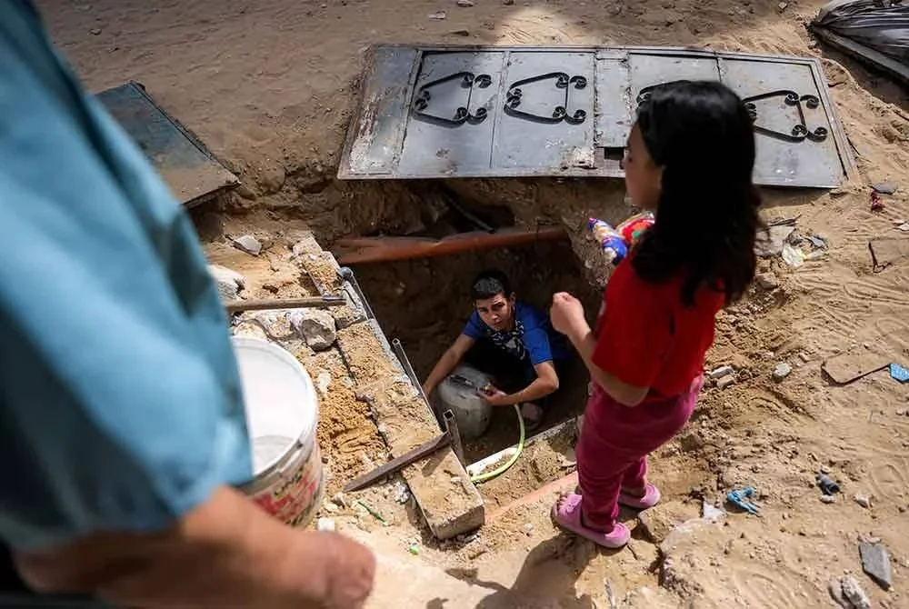 Seorang kanak-kanak lelaki cuba mendapatkan air dari paip bawah tanah yang masih berfungsi di Beit Lahia, utara Gaza.