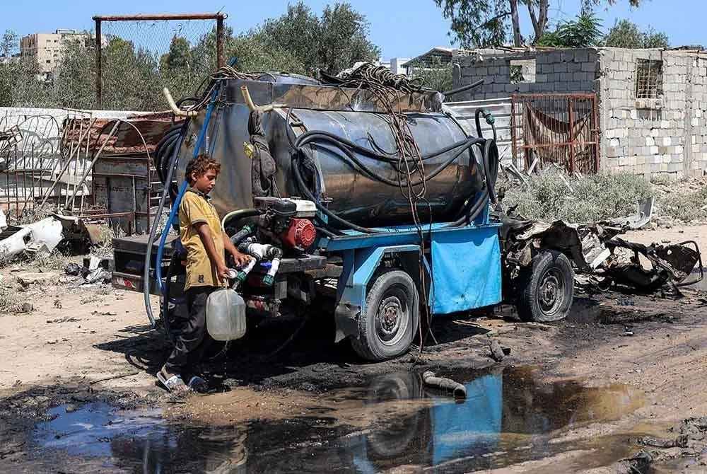 Seorang kanak-kanak lelaki mengisi air dari lori tangki mudah alih yang musnah dibedil Zionis. Foto AFP