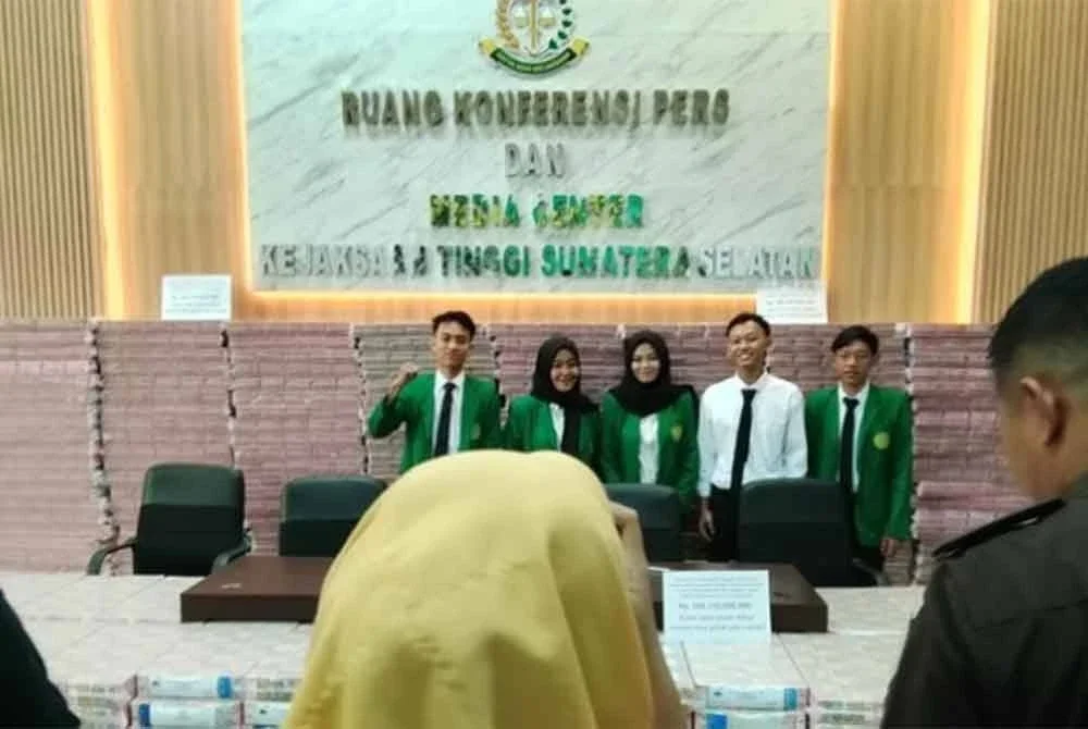 Pelajar yang sedang menjalani latihan industri di pejabat Kejati tidak melepaskan peluang bergambar di hadapan wang tunai yang dirampas. Foto Agensi