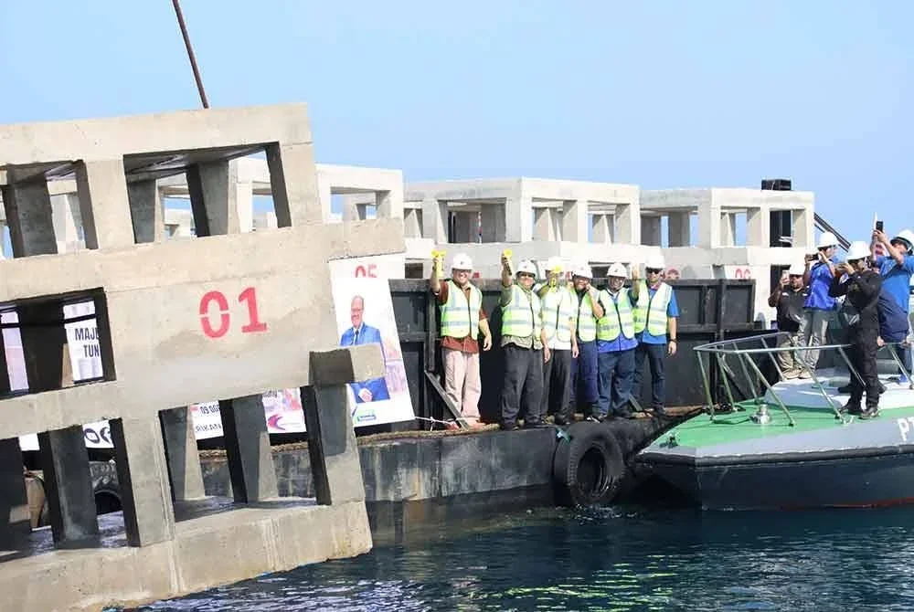 Adnan (kiri) menyempurnakan gimik perasmian melabuh tukun tiruan kuboid penghalang pukat tunda di perairan Pulau Seri Buat dan Pulau Sembilang,Rompin pada Sabtu.