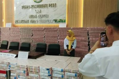 Pelajar teruja bergambar depan wang tunai 506.15 bilion rupiah yang dirampas dalam kes rasuah.