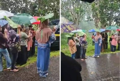 Penduduk menggunakan daun untuk berlindung dari hujan ketika menunggu proses mengali kubur Zara Qairina.