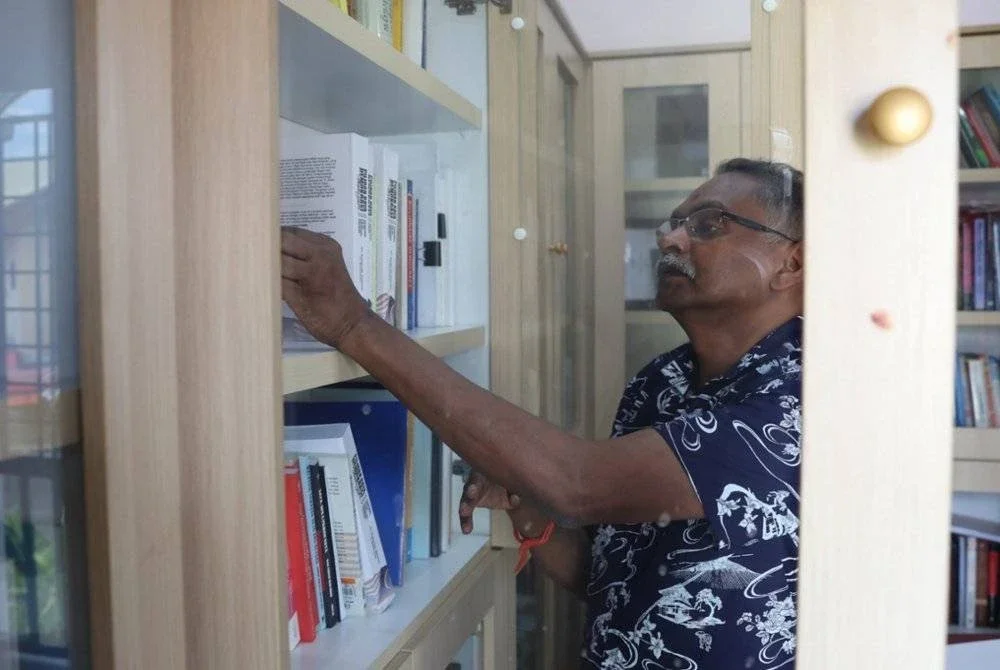 Dr G Manimaran membelek deretan buku ketika ditemubual Bernama di kediamannya di Seksyen 7, Bandar Baru Bangi baru-baru ini.
Dalam era ketika hampir semua orang membaca tajuk berita di media sosial, Manimaran masih membelek muka surat bercetak - bukan satu tetapi 10 akhbar- setiap hari. Foto Bernama