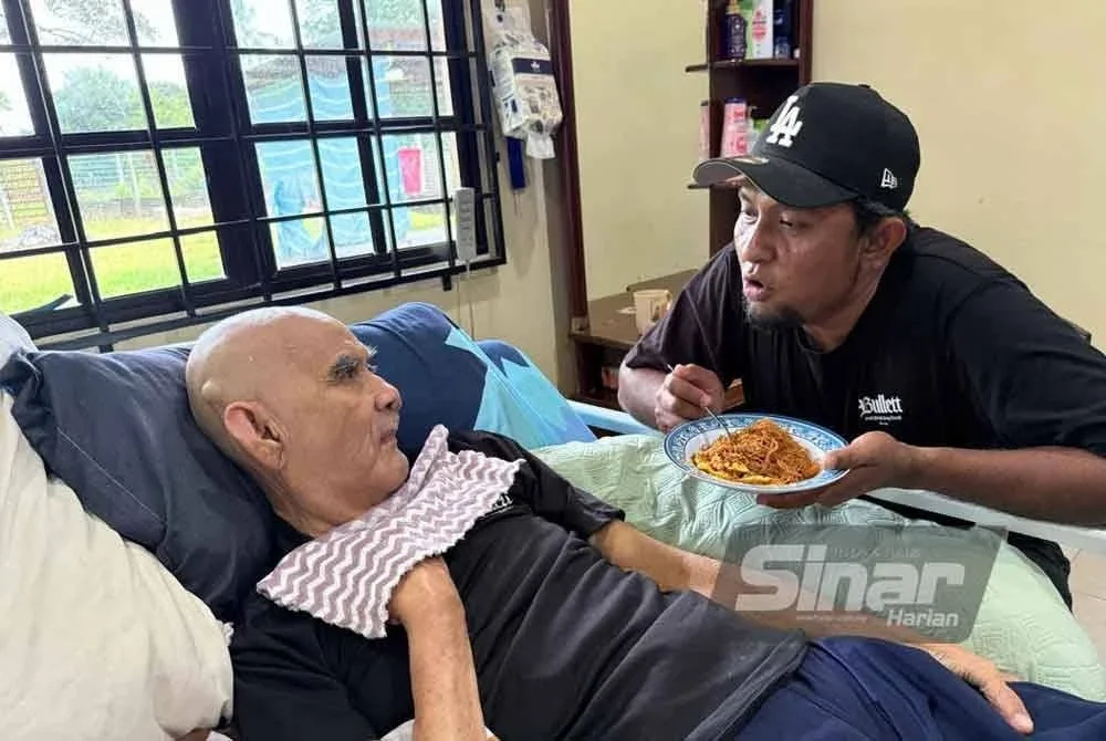 Khairulfahmi (kanan) menjaga bapanya yang uzur sejak 2014.