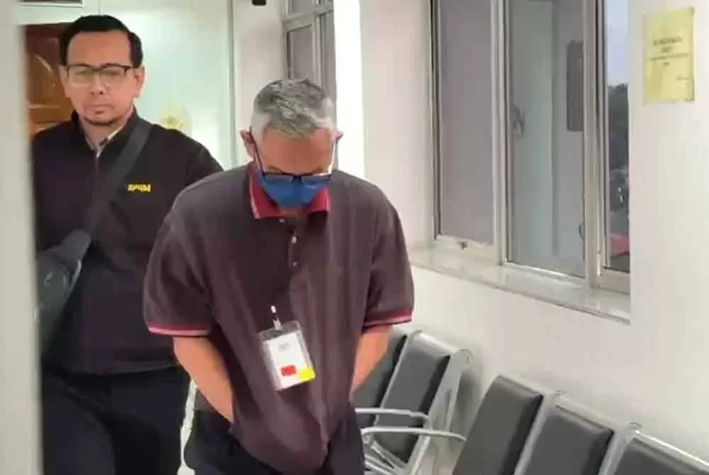 Tertuduh (kanan) ketika dihadapkan di Mahkamah Sesyen Kuala Terengganu pada Isnin.