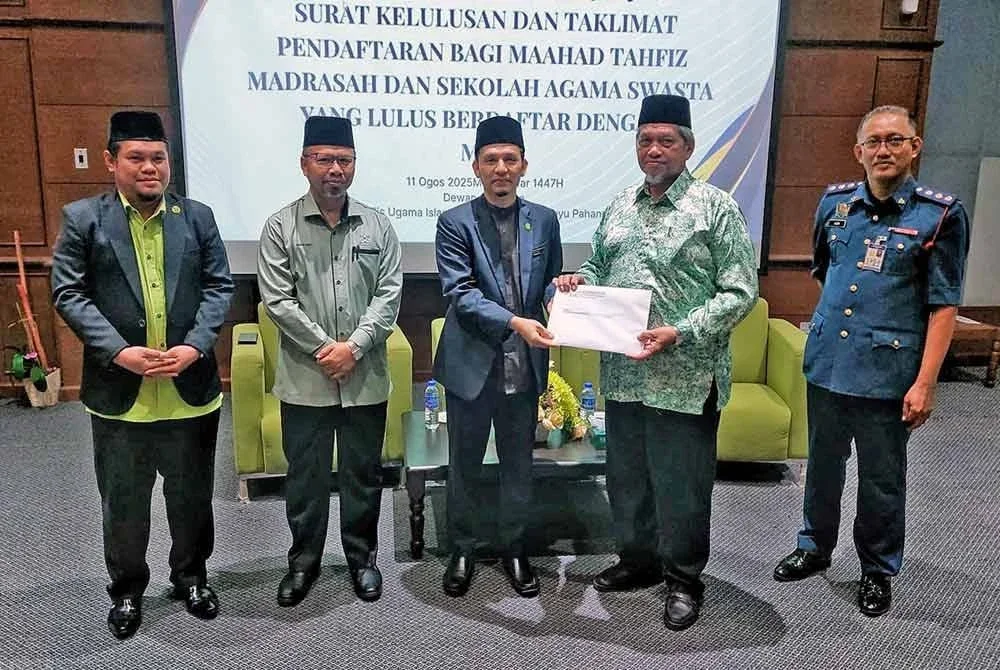 Abdul Zaki (dua dari kanan) mengiringi Mohd Ali (tengah) menyerahkan surat kepada salah seorang penerima pada majlis Penyerahan Surat Pendaftaran Maahad dan Sekolah Agama Swasta di Dewan Syarahan Majlis Ugama Islam dan Adat Resam Melayu Pahang (MUIP) di sini pada Isnin.