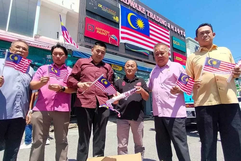 Chin Tian (tiga dari kanan) bersama Mooi Lye (tiga dari kiri) ketika meninjau pemasangan bendera gergasi dihadapan kedainya pada Selasa.