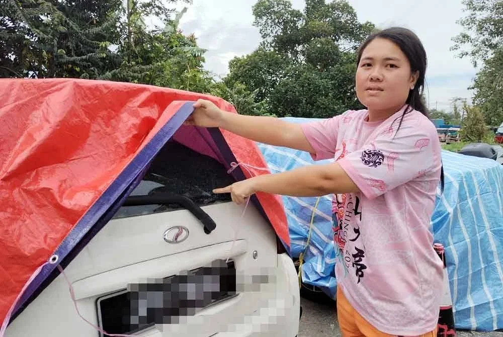 Yuh Hong menunjukkan cermin keretanya yang retak akibat terkena seroihan atap.