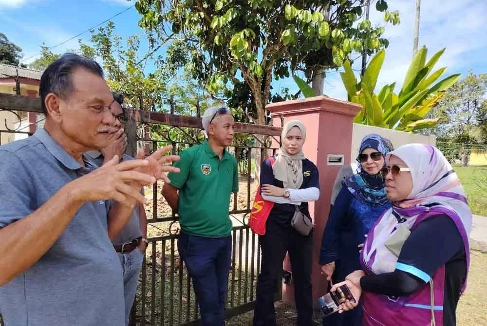 Ismail (kiri) memberikan penerangan kepada Mahfuzah (kanan) yang turun padang meninjau isu sampah di Batu 16, Kampung Haji Palil, Dusun Tua.