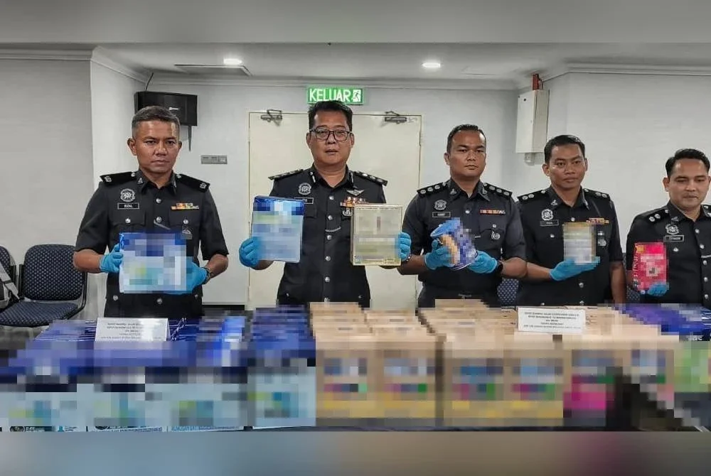 Christopher (dua, kiri) menunjukkan susu formula yang dirampas dalam serbuan itu.