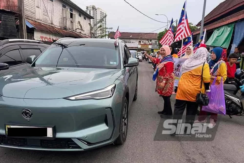 Dr Hafidzah (kanan) turut mengagihkan bendera kepada pengguna jalan raya. Foto SINAR HARIAN/ADILA SHARINNI WAHID