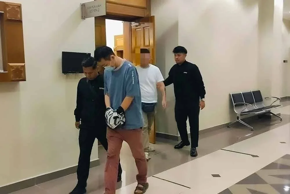 Tertuduh diiringi pegawai SPRM keluar dari mahkamah selepas dijatuhi hukuman atas kesalahan menyogok polis tahun lalu.