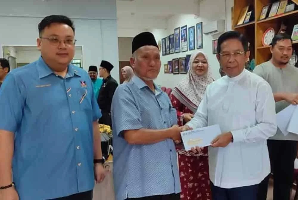 Jalaluddin (kanan) menyampaikan sumbangan bantuan mingguan kepada penerima.
