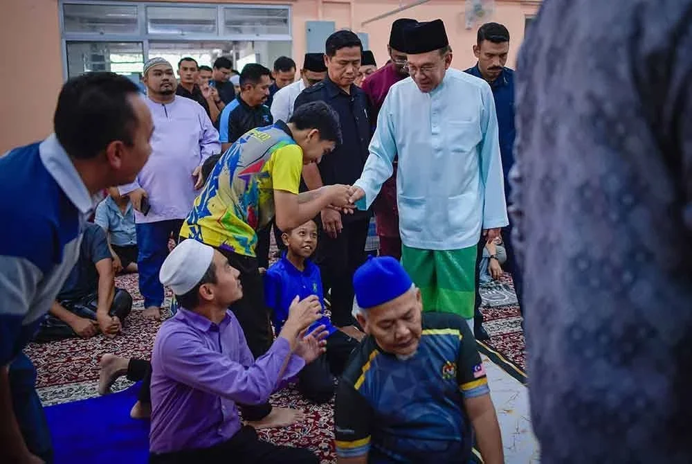 Anwar menyantuni jemaah sebelum menunaikan solat Jumaat di Surau Al-Muttaqin 5R6, Putrajaya. Foto Bernama