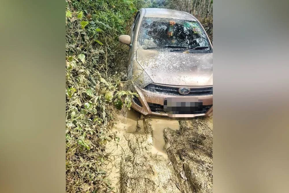 Keadaan kereta pemandu Grab yang tersesat di kawasan berlumpur di sebuah ladang sawit di Alor Gajah pada Jumaat.
