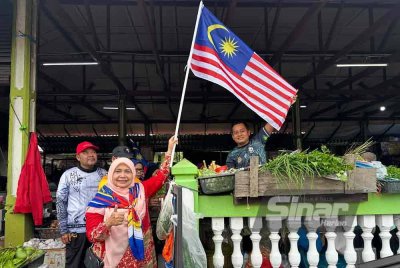 Dr Hafidzah (tengah) memacakkan Jalur Gemilang di pagar Pasar Kubang Pasu di Kota Bharu. Foto SINAR HARIAN/ADILA SHARINNI WAHID