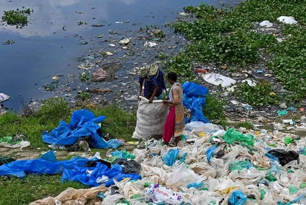 Pengutip sampah mengasingkan beg plastik untuk dikitar semula di Dhaka.