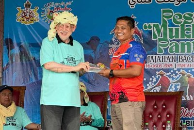 Kamarudin (kiri) menyampaikan hadiah wang tunai RM1,000 kepada peserta juara memukat ikan dari APM.