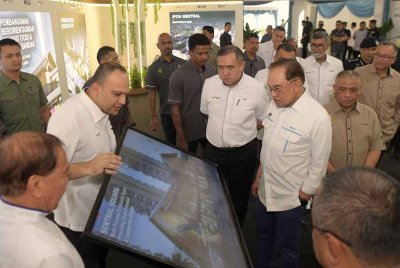 Anwar (tiga, kanan) mendengar taklimat daripada Pengarah Urusan Kumpulan MRCB, Datuk Imran Salim (dua, kiri) ketika melawat reruai pada Majlis Pecah Tanah Pembangunan Ipoh Sentral di pekarangan Stesen Keretapi Ipoh pada Sabtu. Foto Bernama