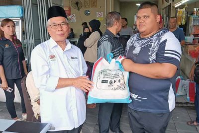 Hassan (kiri) ketika menyampaikan sumbangan di Kampung Bendara pada Ahad.