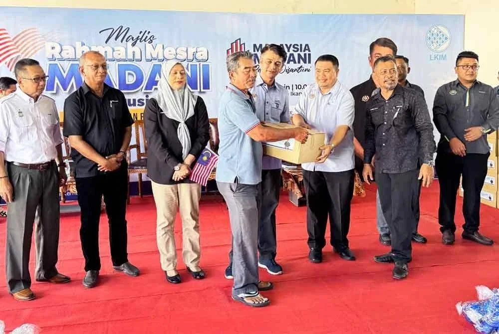 Muhammad Faiz (empat dari kiri) menyerahkan bantuan kepada nelayan ketika Program Rahmah Mesra Madani Bersama Nelayan Pulau Pinang di Jelutong pada Isnin.