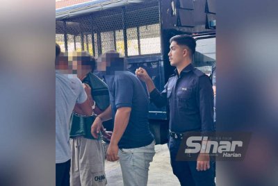 Suspek berusia 23 tahun (kiri) dan abangnya yang berusia 34 tahun dikawal polis semasa tiba di Kompleks Mahkamah Kota Bharu.