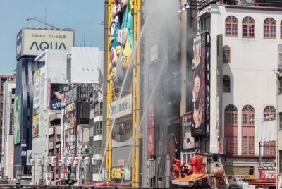 Semburan air digunakan oleh anggota bomba untuk memadamkan kebakaran bangunan di kawasan tumpuan pelancong dan membeli-belah popular di pusat bandar Osaka pada 18 Ogos 2025. Foto AFP