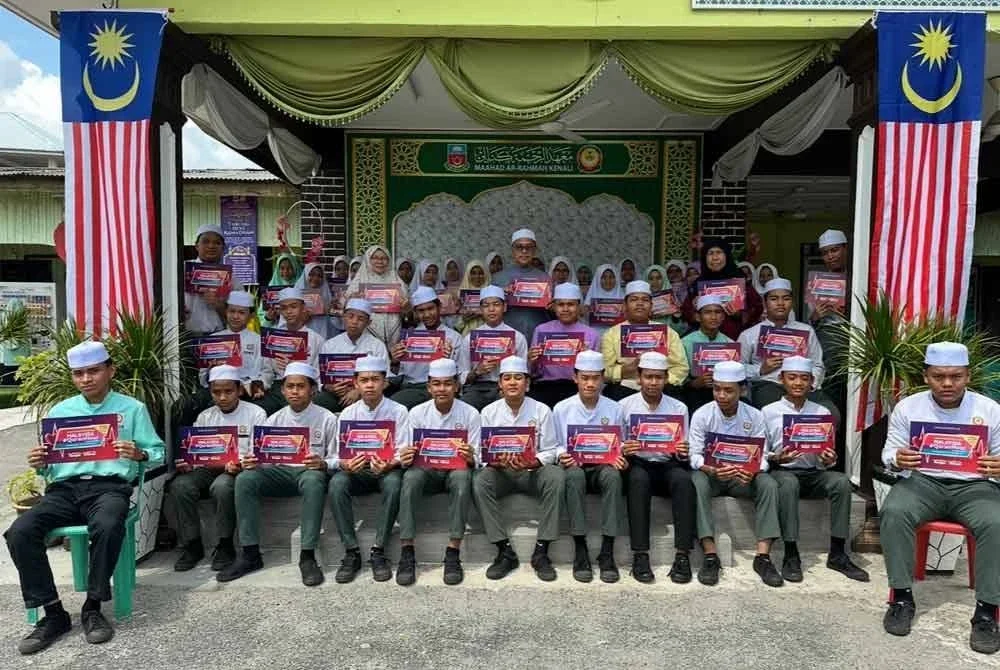 Pelajar Maahad Ar-Rahmah Kenali memegang risalah Malaysia #QuranHour 2025 sebagai tanda sokongan.