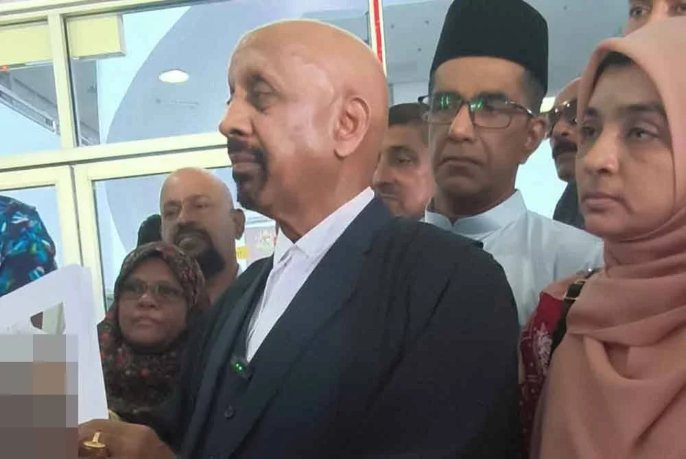 Naran Singh menunjukkan gambar Syamsul Haris yang dilampirkan dalam notis usul, dengan ditemani Ummu Haiman Bee dan ahli keluarga Allahyarham, di Mahkamah Tinggi Shah Alam pada Selasa.