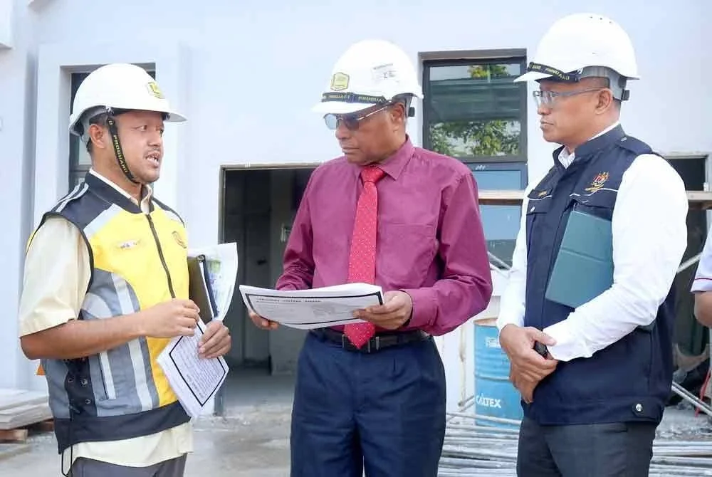 Sivanesan (tengah) mendengar penjelasan daripada wakil Jabatan Kerja Raya mengenai perkembangan pembinaan bangunan Klinik Kesihatan Manjoi dalam lawatan kerja ke klinik tersebut di Ipoh pada Selasa.