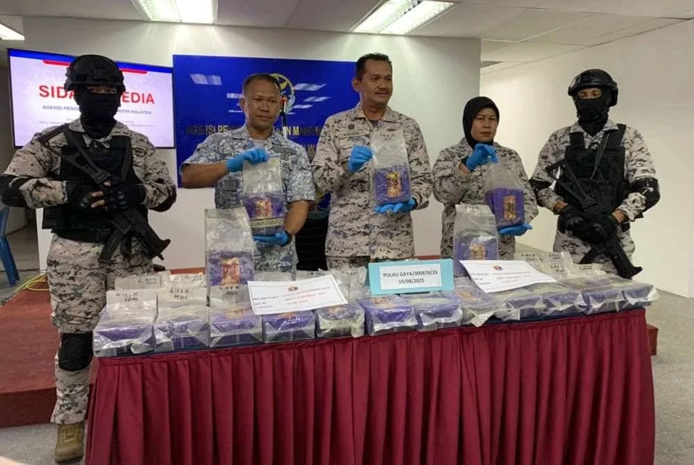 Mohd Khairulanuar (tengah) menunjukkan dadah yang ditemui di sebuah kapal pemancing di perairan Kota Kinabalu.