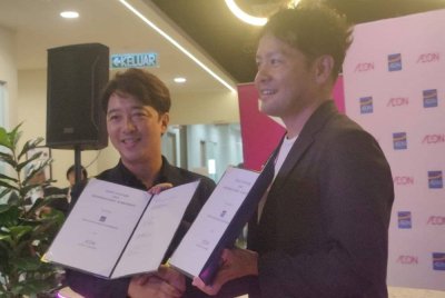 Daisuke (kiri) dan Naoya (kanan) bertukar dokumen perjanjian semasa Majlis Menandatangani Usaha Sama antara AEON Credit dan AEON Malaysia pada Selasa.