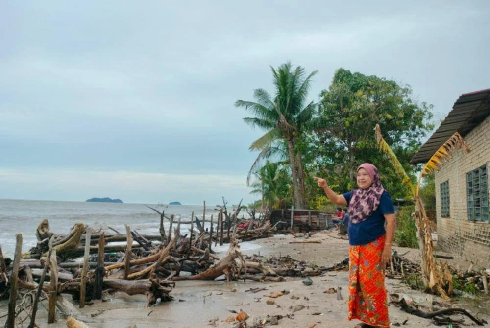 Pazidah menunjukkan jarak belakang rumah yang tinggal beberapa langkah sahaja akibat hakisan.
