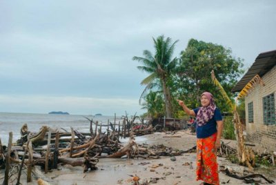 Pazidah menunjukkan jarak belakang rumah yang tinggal beberapa langkah sahaja akibat hakisan.