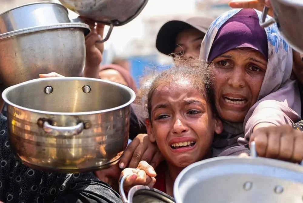 Penduduk Palestin beratur menerima makanan di pusat agihan di Bandar Gaza. - AFP