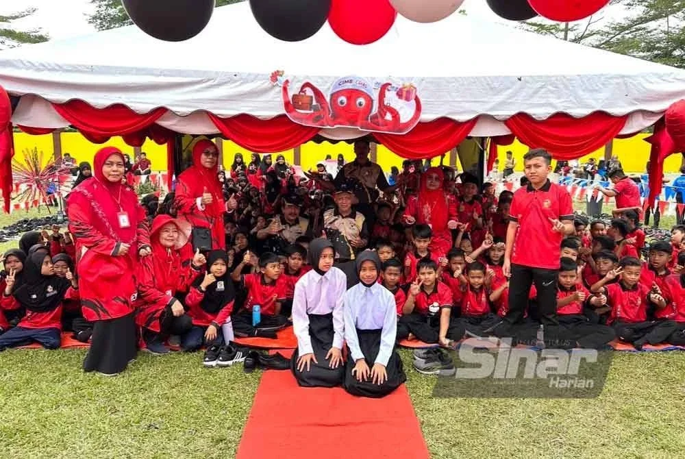 Muhammad Nasir (tengah) dan Mohd Nawawi (kiri) bergambar bersama murid di khemah rumah sukan.