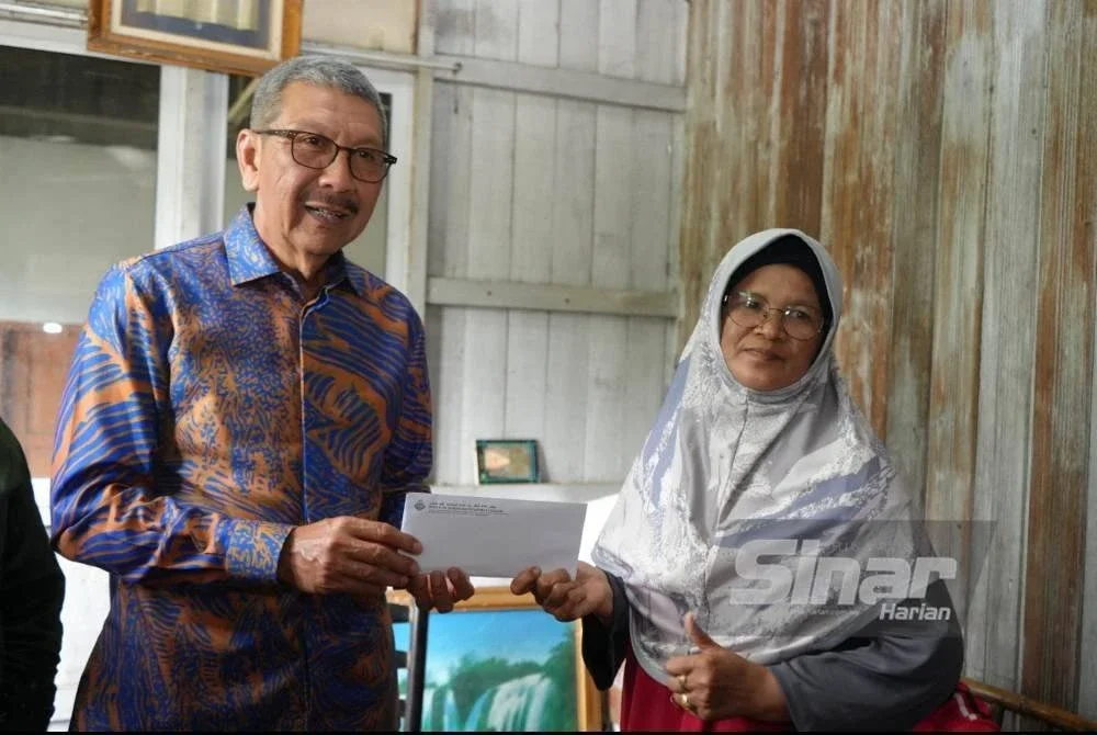 Wan Ahmad Dahlan (kiri) menyampaikan sumbangan kepada Siti Rubiah (kanan).