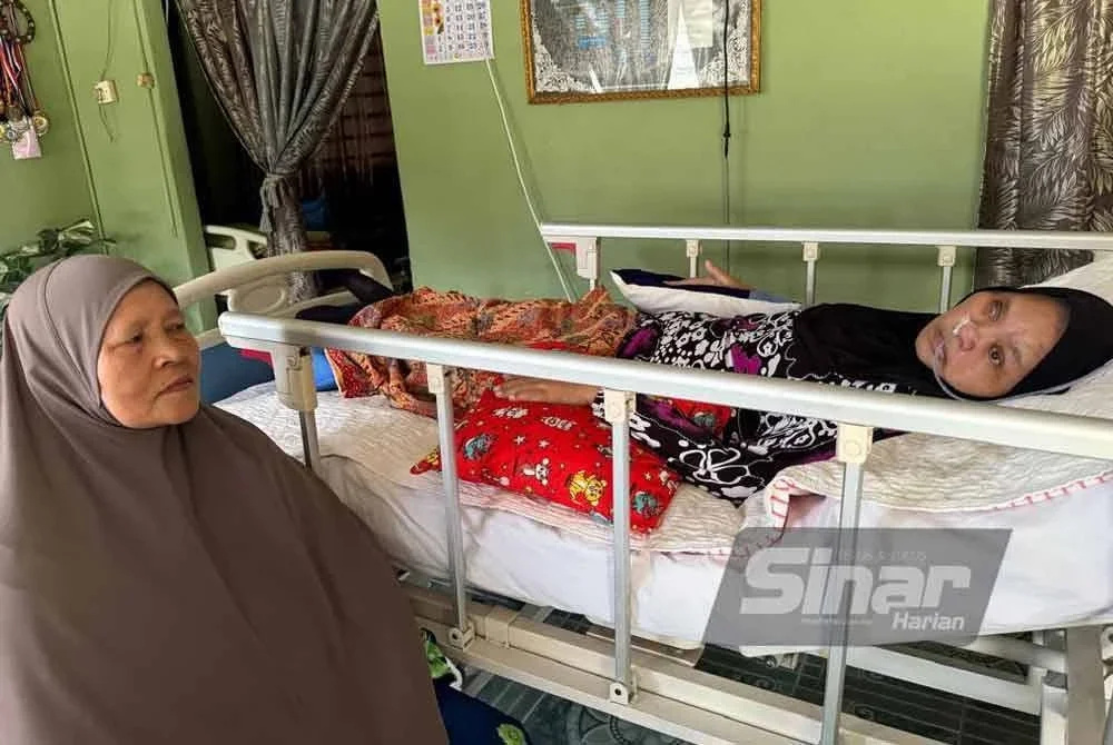 Azizah (kiri) setia menemani anak sulungnya, Anisah yang kini sakit terlantar akibat strok.