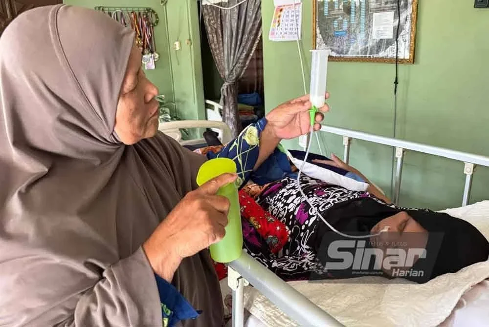 Azizah (kiri) memberikan susu khas kepada anaknya yang terlantar akibat strok.