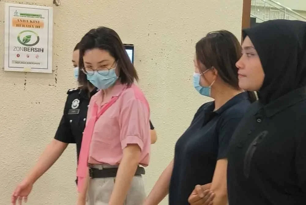 Shin Yin (kiri) dan adiknya, Shin Hua (dua dari kanan) mengaku tidak bersalah di dua Mahkamah Sesyen Kuala Lumpur pada Jumaat atas pertuduhan pecah amanah.