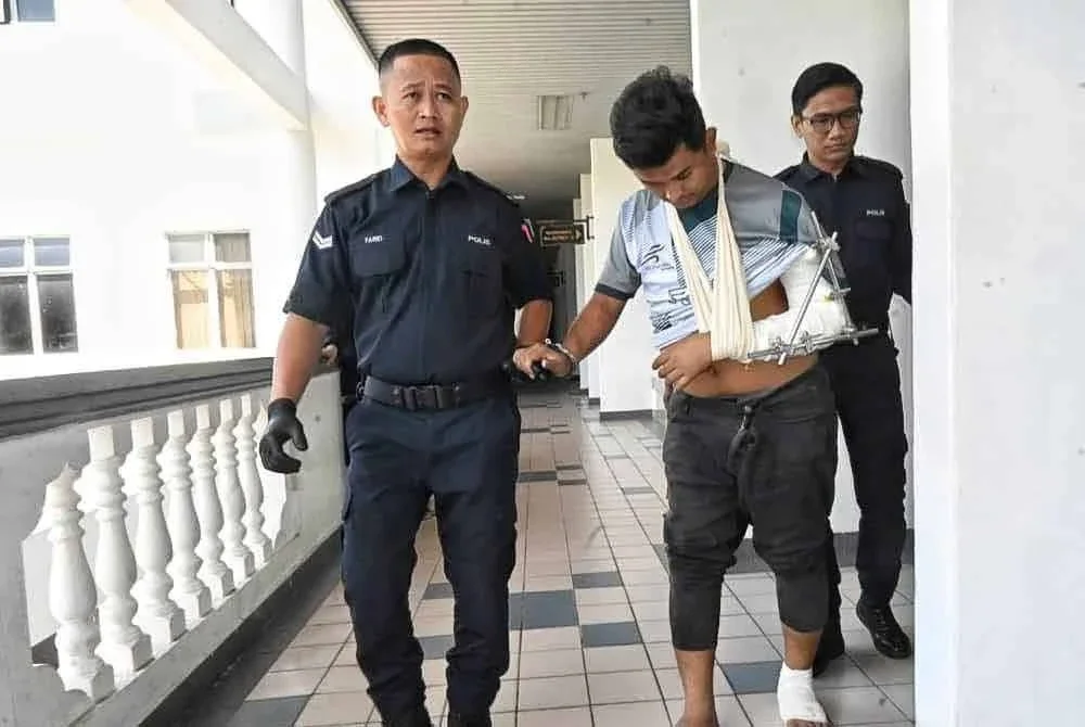 Tertuduh (tengah) ketika dibawa keluar dari Mahkamah Majistret pada Jumaat.