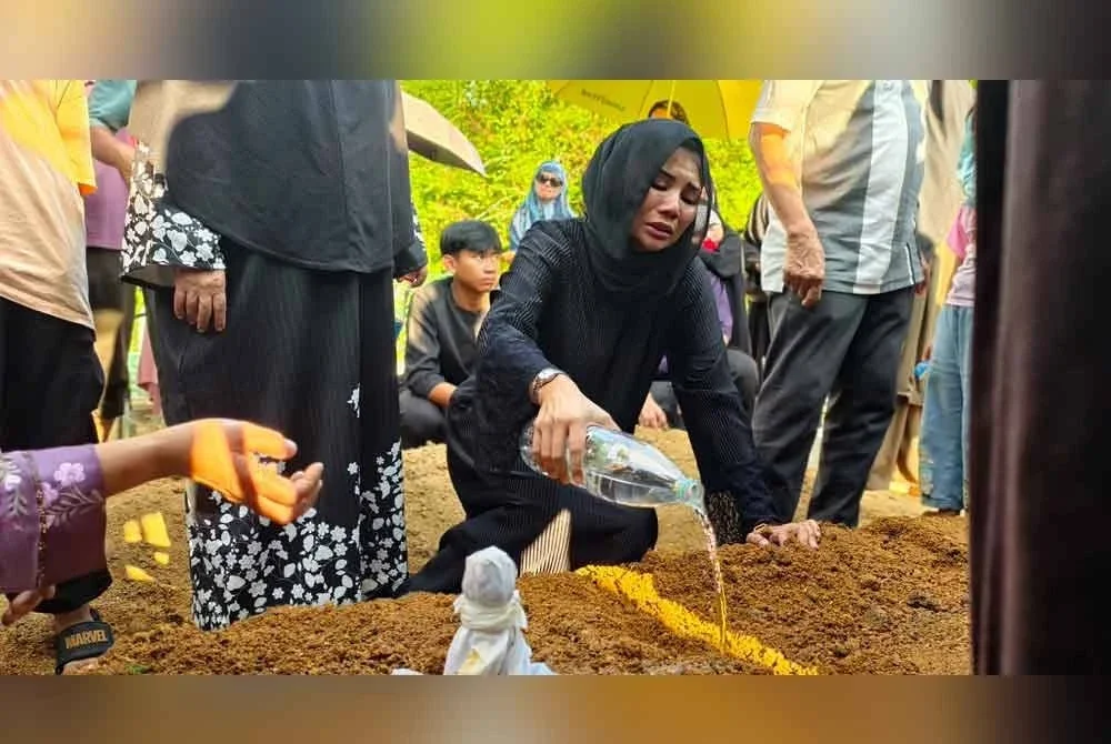 Nurul Wahida tidak dapat menahan kesedihan ketika menyiram air di pusara Allahyarham yang selamat dikebumikan.