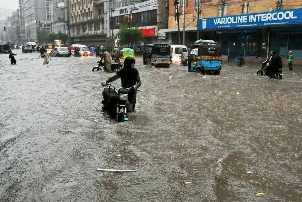 Orang ramai meredah jalan yang dinaiki air selepas hujan lebat melanda Karachi. Foto: AFP