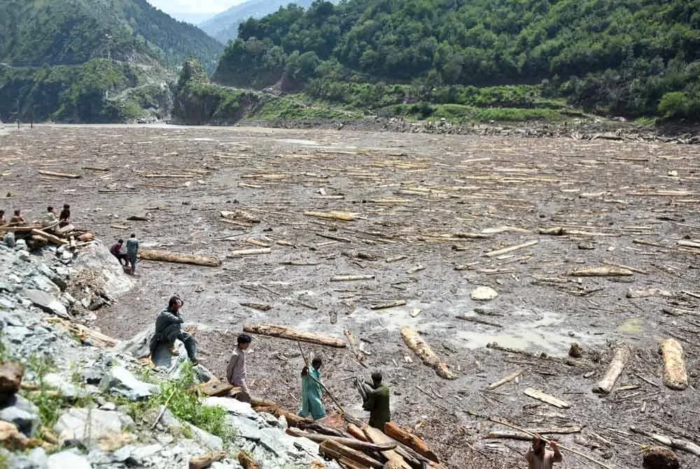 Penduduk tempatan mengutip kayu dihanyut banjir di Empangan Noseri berhampiran Muzaffarabad, sehari selepas banjir melanda. Foto: AFP
