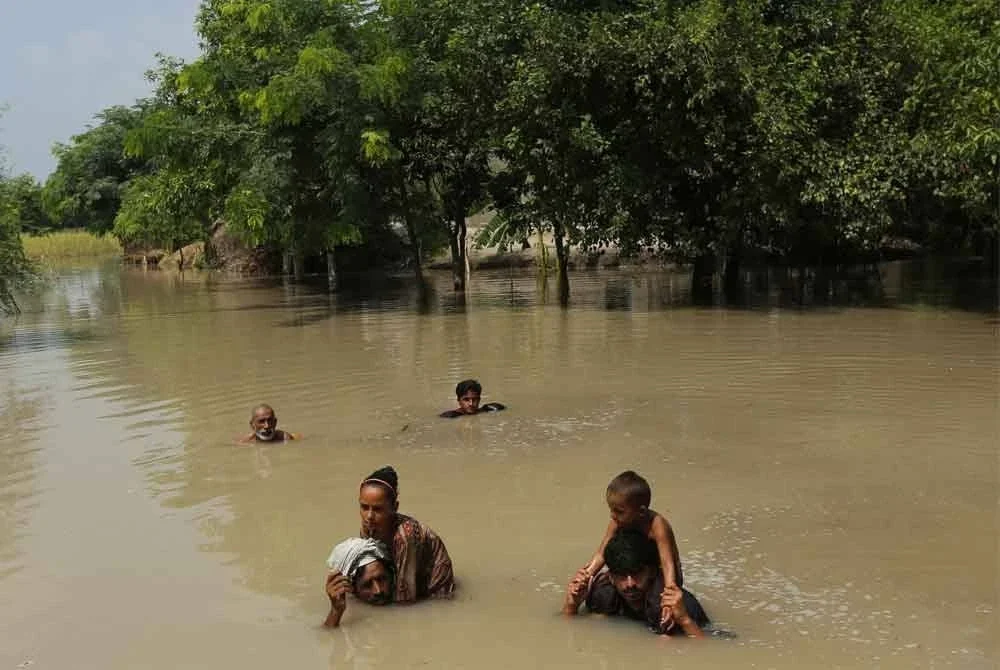 Penduduk kampung meredah banjir selepas hujan lebat di Kampung Ehsan Pur, daerah Kot Addu, wilayah Punjab. Foto: AFP