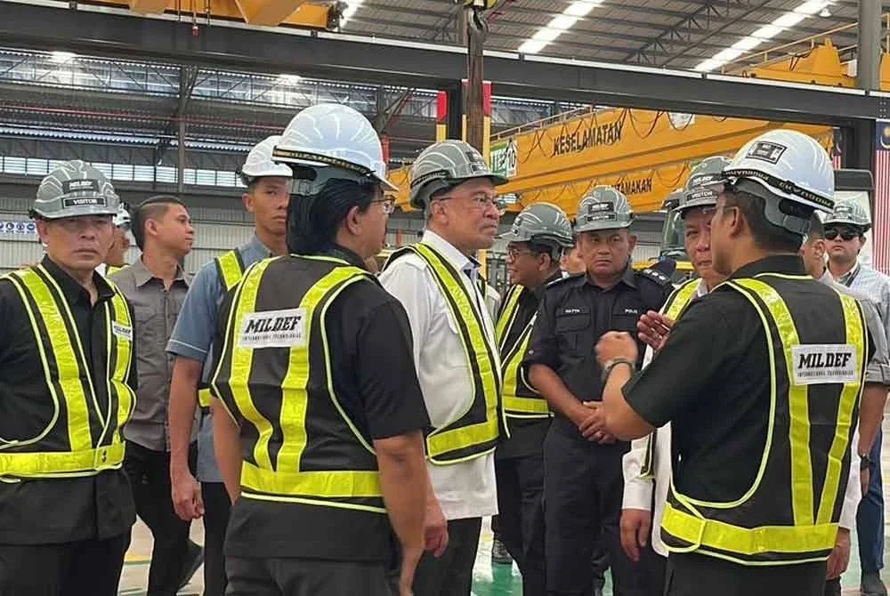 Anwar mendengar penerangan ketika meninjau kilang pembuatan kenderaan perisai Mildef International Technologies di Sendayan pada Sabtu.