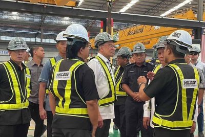 Anwar mendengar penerangan ketika meninjau kilang pembuatan kenderaan perisai Mildef International Technologies di Sendayan pada Sabtu.