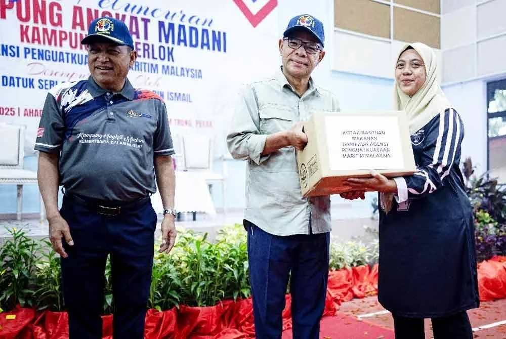 Saifuddin Nasution (tengah) menyampaikan kotak bantuan makanan kepada masyarakat setempat, Roshidah Taha (kanan) pada Majlis Peluncuran Kampung Angkat Madani Maritim Malaysia Tahun 2025 di Dewan Perdana Mukim Trong, Taiping hari ini. - Foto: Bernama