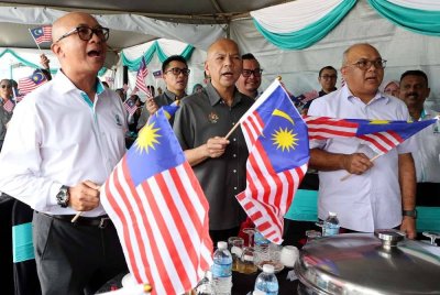 Armizan (depan, tengah) mengibarkan Jalur Gemilang bersama kakitangan Stesen Minyak Petronas Papar pada majlis penyerahan Kit Jalur Gemilang dan pelancaran Kempen Love Local di Stesen Minyak Petronas Papar hari ini. Foto Bernama